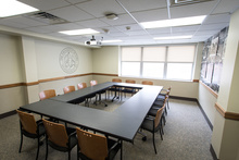 Four tables in square with fourteen chairs, window, wall displays.