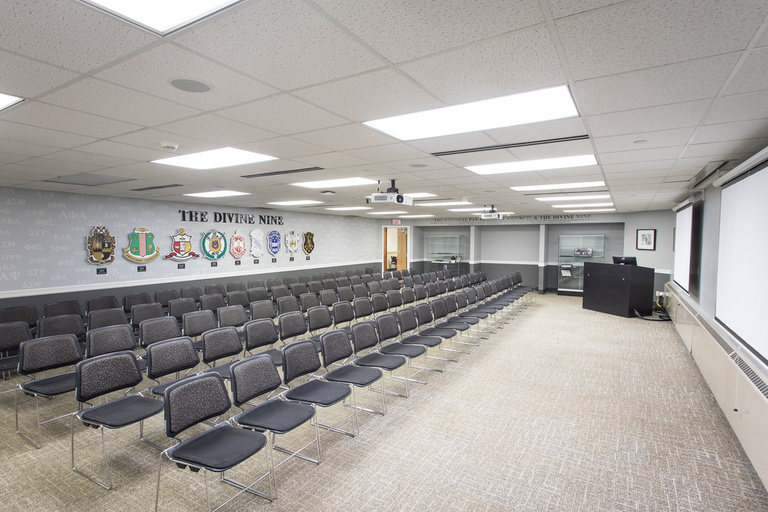 Alternate angle of five rows of twenty chairs each with a whiteboard, projector, and podium. 