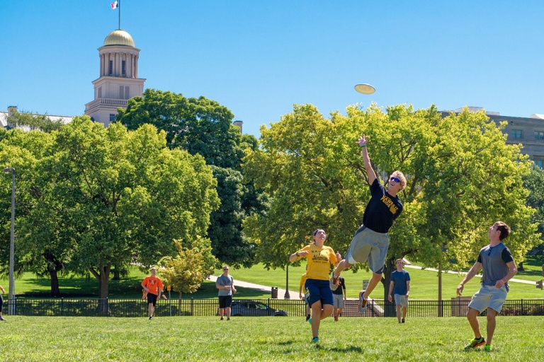 student jumping to catch frisbee in park