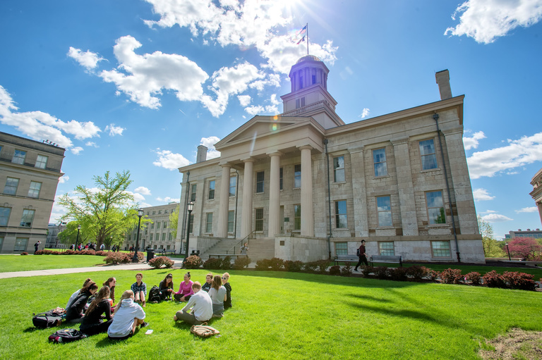 students sitting on grass in front of the old capitol building