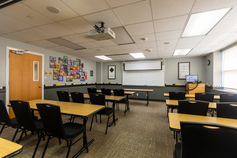Tables, chairs, projector, and whiteboard with colorful signage