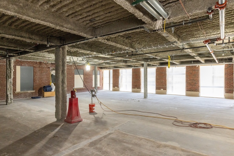 Open floor with windows and brick in the background.