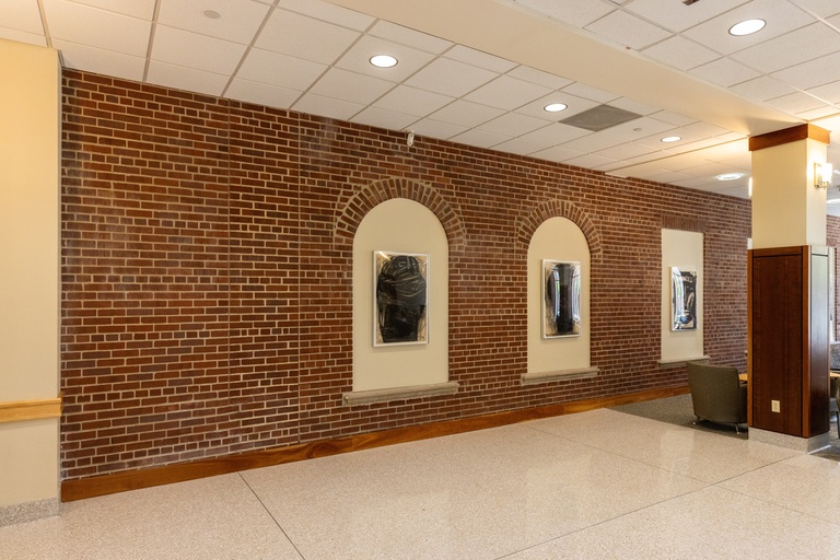 Brick wall with artwork hanging in Hubbard Commons space.