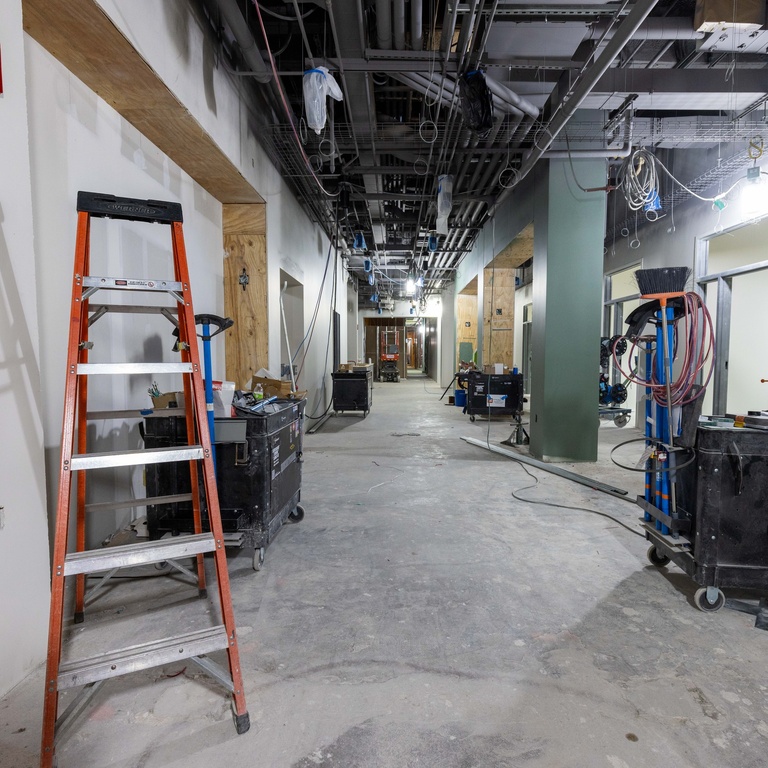 A ladder is seen in the hall of the wellness center looking east, along with painted walls and columns.