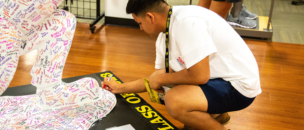 freshman student signing herky with marker