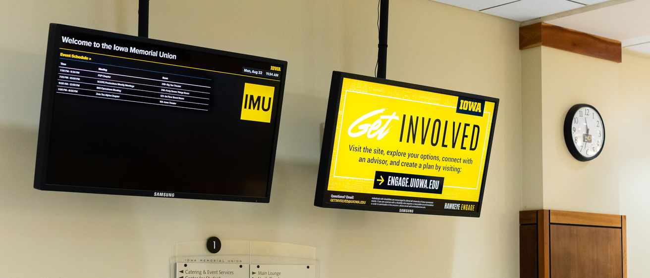 Two digital signage screens showing a building schedule and flyers in the IMU