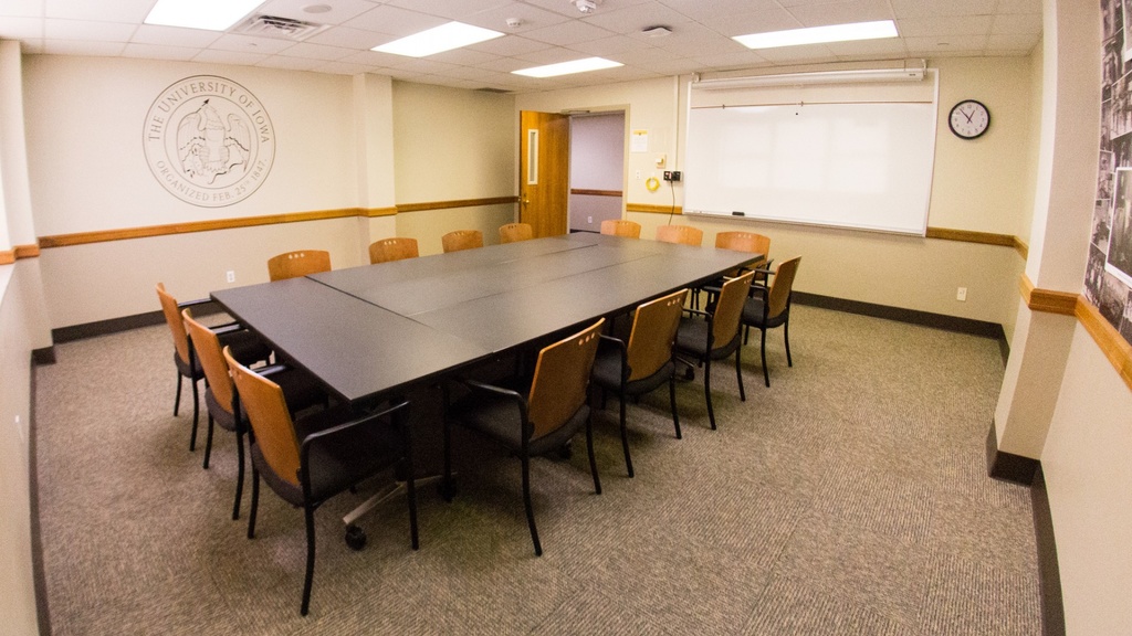 Five tables pressed together with fourteen chairs, whiteboard.