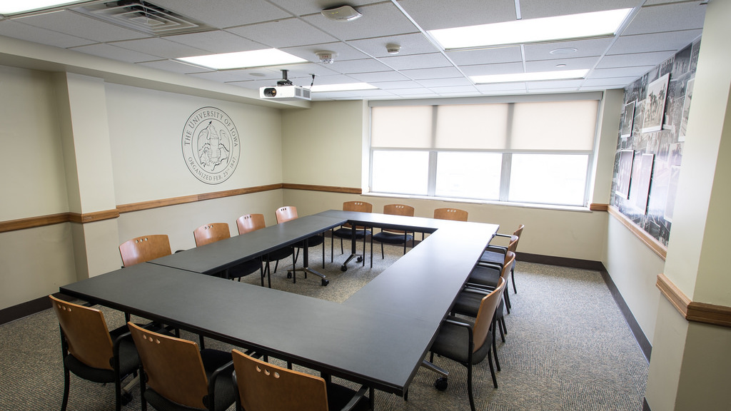 Four tables in square with fourteen chairs, window, wall displays.