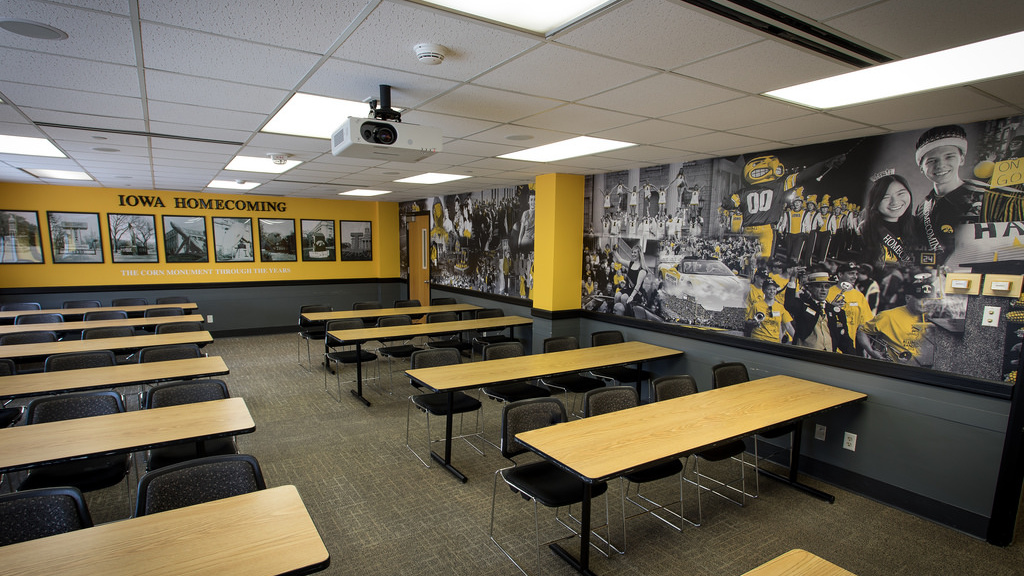 Ten tables each with four chairs facing front and center table and chairs, walls featuring display of homecoming photos.