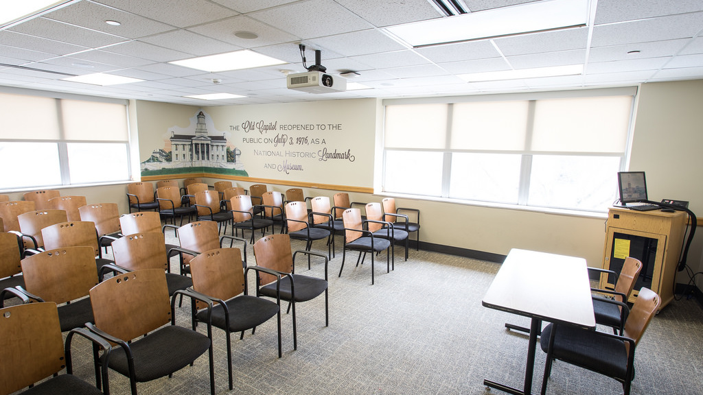 Six rows of seven chairs each facing a front and center table with two chairs.