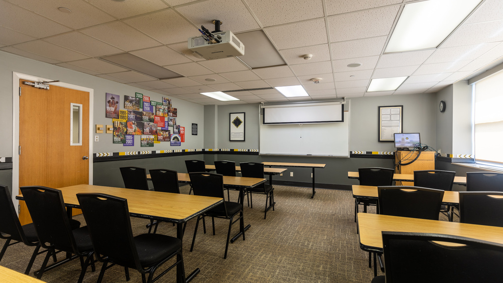 Tables, chairs, projector, and whiteboard with colorful signage