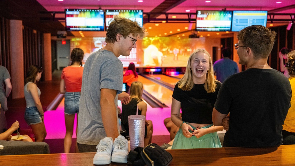 Students hanging out at a bowling alley, laughing and talking.