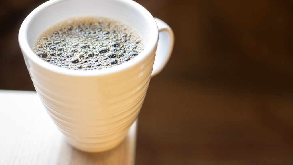 Coffee mug filled with coffee sitting on the edge of a counter.