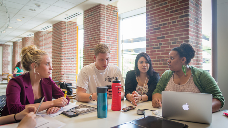 four students studying at table